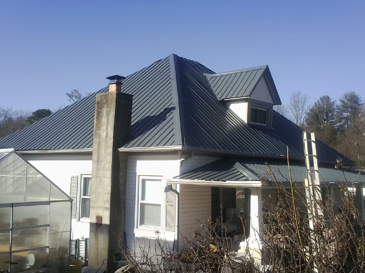 Dark blue standing seam metal roof on a white farmhouse with dormer — Slate & Tile Roof Repair by Roofing Brothers in Narvon