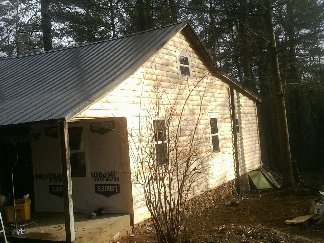 Log siding gable end under a dark metal roof edge in Narvon