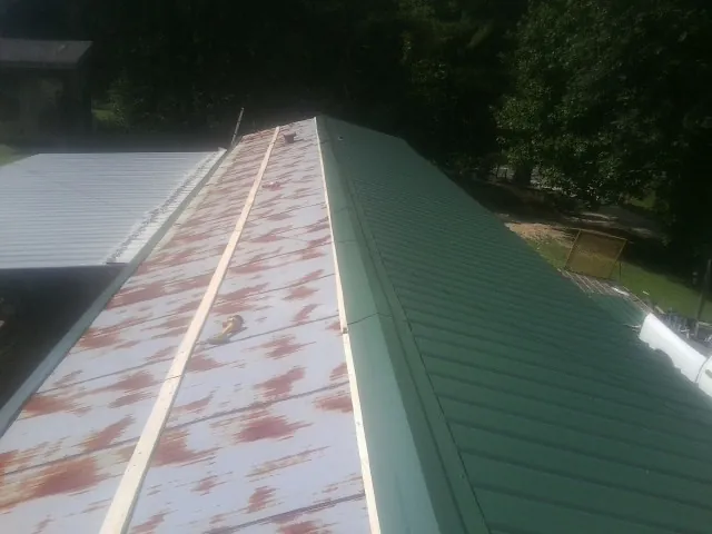 Old rusted panels beside newly installed green metal roofing — Wind Damage Roof Repair by Roofing Brothers in Narvon