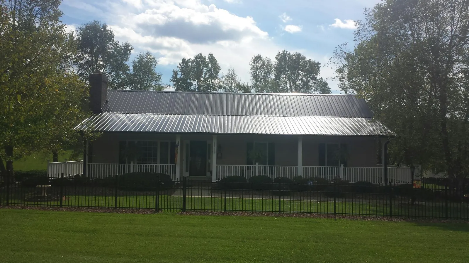 Gray metal roof on a brick ranch with a full width front porch — Gutter Guard Installation work by our crew in Narvon