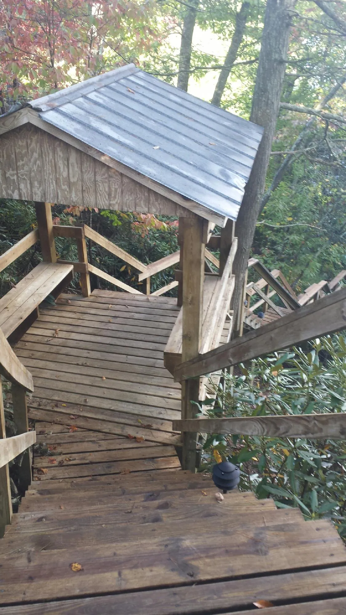 Metal roofed shelter over wooden steps on a wooded walkway — Skylight Repair & Installation work by our crew in Narvon