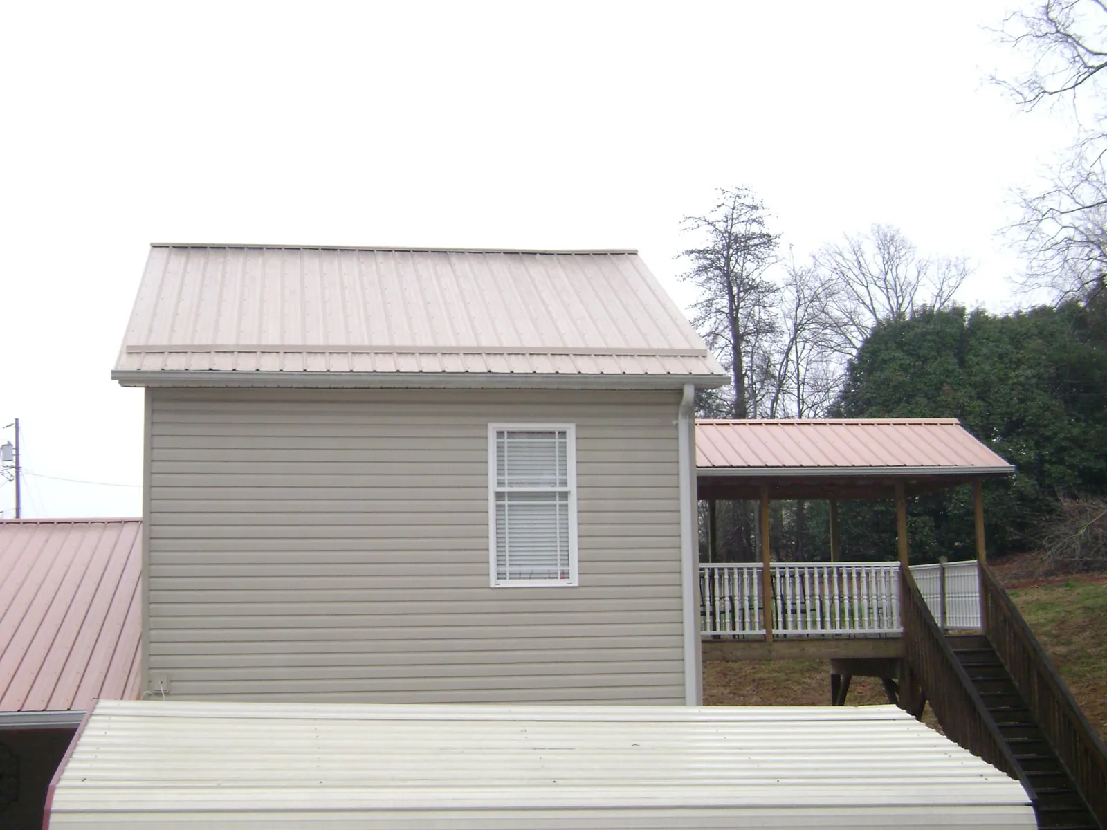 Tan metal roofs on a two story addition and attached porch, from a Roof Replacement job in Narvon