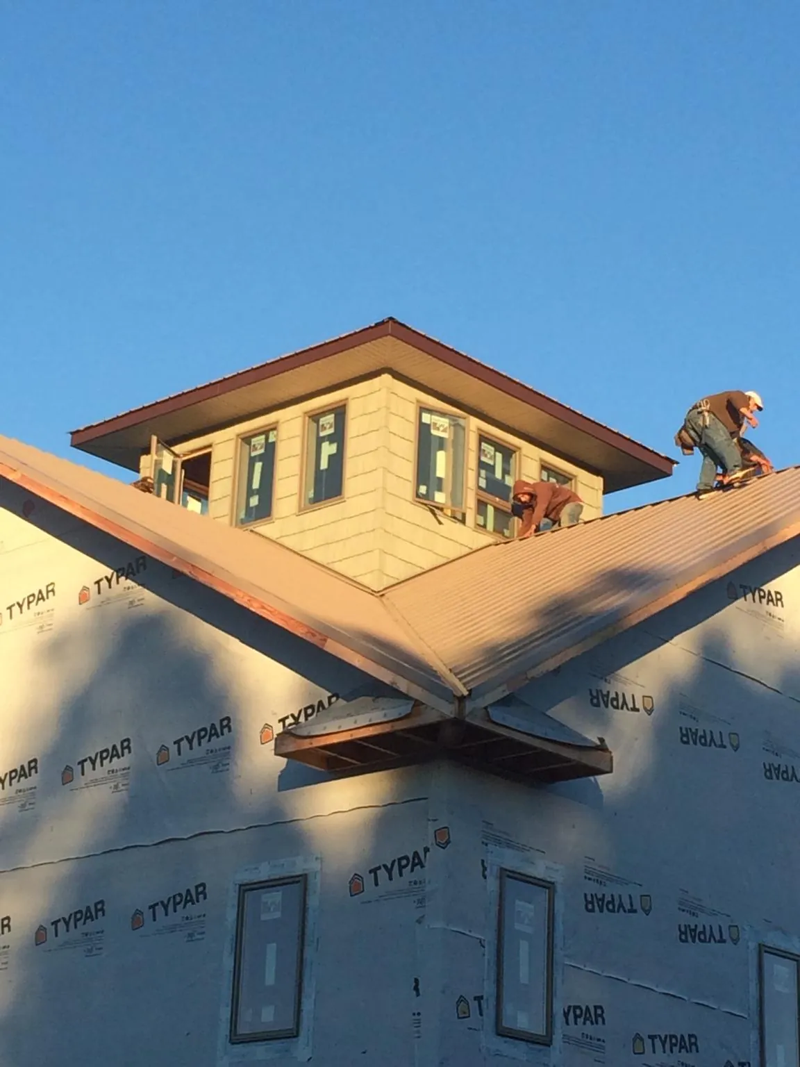 Roofers working around a rooftop cupola on a new metal roof at sunset — Roof Waterproofing in Narvon by Roofing Brothers